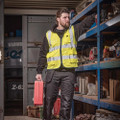 Scruffs High Visibility Mens Hi-Viz Technical Zip Up Vest, bright yellow high visibility vest with reflective strips worn by a man working in a workshop or warehouse.
