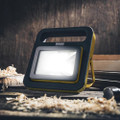 Defender 20W 30W 50W Slimline LED Floor Light Wired Floodlight, modern portable LED floodlight illuminating a workspace with wood shavings.