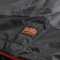Scruffs Tech Mens Zip Up Work Warm Hooded Jacket Coat, close-up of the black fabric with orange and black label detailing the brand and model number.