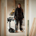 Scruffs Trade Flex Womens Trouser Codura Stretch Workwear Trousers, a woman wearing black work trousers with reinforced and stretchable fabric, standing in a construction site with tools.