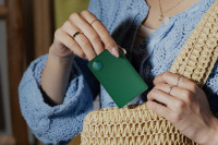 A Life360 Tile Slim - Green Surf being placed inside of a handbag.