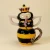 Bring a little royal charm to your tea time with the whimsical and beautifully detailed Tea With Queen Tea For One Set. Designed as an adorable queen bee complete with delicate wings, floral accents, and a golden crown, this playful ceramic tea set stacks together into one enchanting display piece that’s as decorative as it is functional.

Featuring glossy hand-painted details and soft floral touches, this charming tea-for-one includes a teapot and matching cup perfectly sized for cozy solo tea moments. Whether displayed on a kitchen shelf, tea station, or gifted to a tea lover, this delightful queen bee design adds personality, sweetness, and storybook charm to any space. ??

Details:
- Features floral accents, delicate wings, and hand-painted details
- Perfect for tea lovers, cottagecore, whimsical, or garden-inspired décor
- A charming gift for collectors, bee lovers, and afternoon tea enthusiasts

Dimensions: 8" x 4.25" x 9"
Ceramic