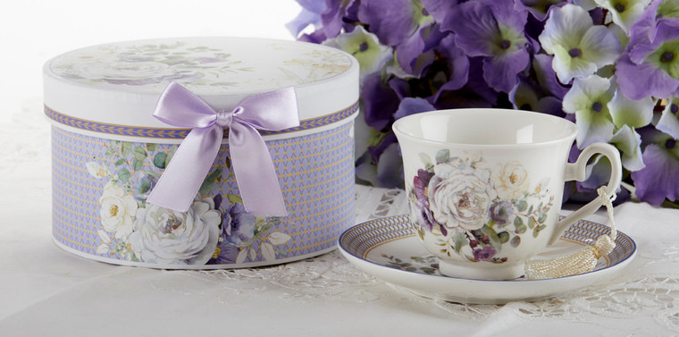 Purple Elegance Cup/Saucer in Gift Box Cup/Saucer in gift box, will brighten anyone's day in its own matching print gift box with matching satin ribbon. A decorative tassel on the handle adds a lovely finishing touch. Gifting Idea: birthday gift, bridal shower, get well, treat yourself or someone you love.   Includes:  3.5" Cup/Saucer in gift box Soft white background with purple, gold and white floral print Dishwasher safe