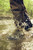 Outdoorsman wearing Dan’s Brush Buster Froglegs while crossing wet and muddy hunting terrain