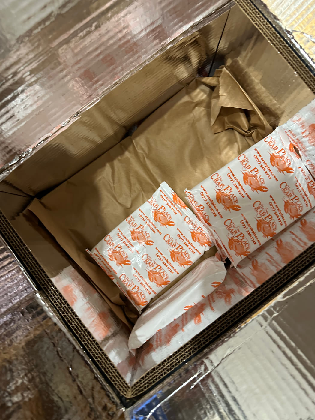An opened Crab Place delivery box with branded insulated wraps, viewed from above