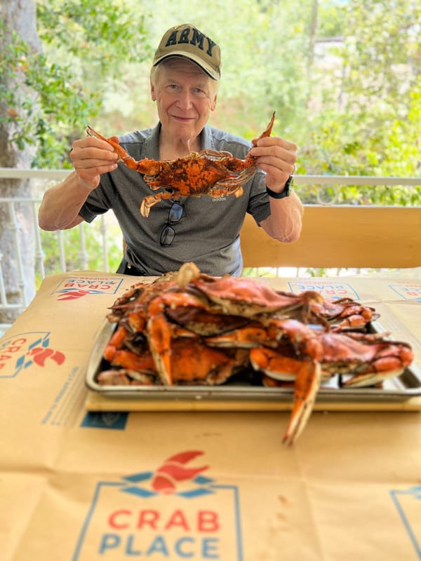 Customer in an Army cap holding up a steamed crab over a tray