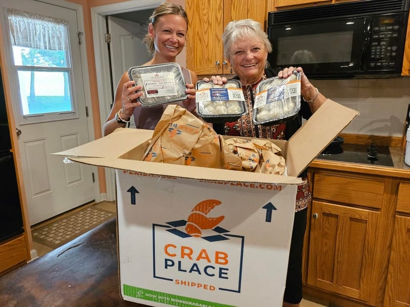 Two women unboxing a Crab Place delivery in the kitchen