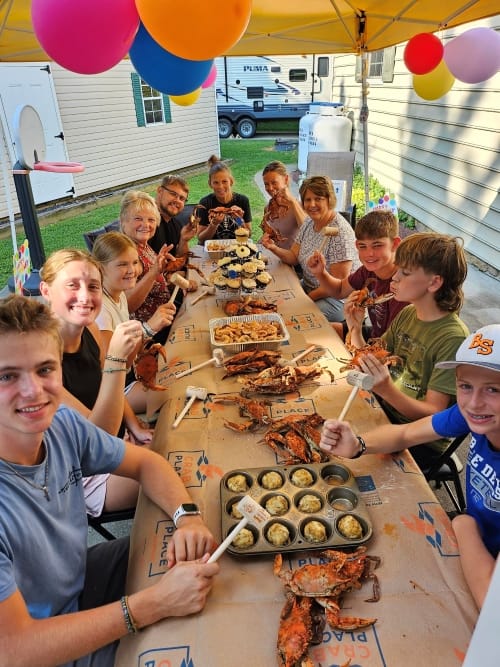 A backyard party table covered in Crab Place paper and steamed crabs