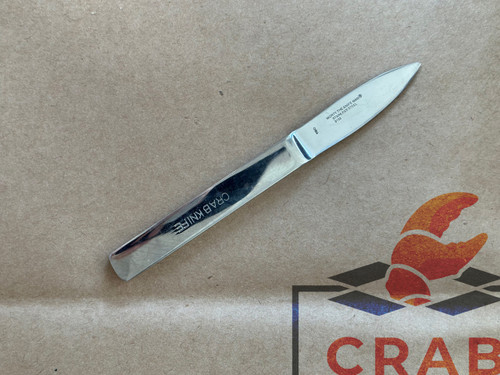 Stainless steel crab picking knife with Crab Knife stamped on the handle, lying on a box with a crab logo.