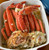 Snow crab clusters in a white baking dish with butter sauce, chopped onion, herbs, and paprika-dusted cabbage.