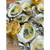 Grilled oysters on the half shell topped with herb butter, charred lemon wedge, and fresh chives.