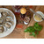 Shucked oysters on a white plate with melted butter, cocktails, and fresh herbs on a branded wooden board.