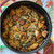 Cooked oyster and sausage stuffing with potatoes in a red cast-iron Dutch oven, viewed from above.