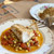 Seared Alaskan black cod fillet over cherry tomatoes and corn, with a forkful lifted and a crumb-topped fillet behind it.