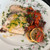 Seared Canadian swordfish steak drizzled with olive oil, topped with parsley, beside roasted tomatoes, olives, capers and lemon.
