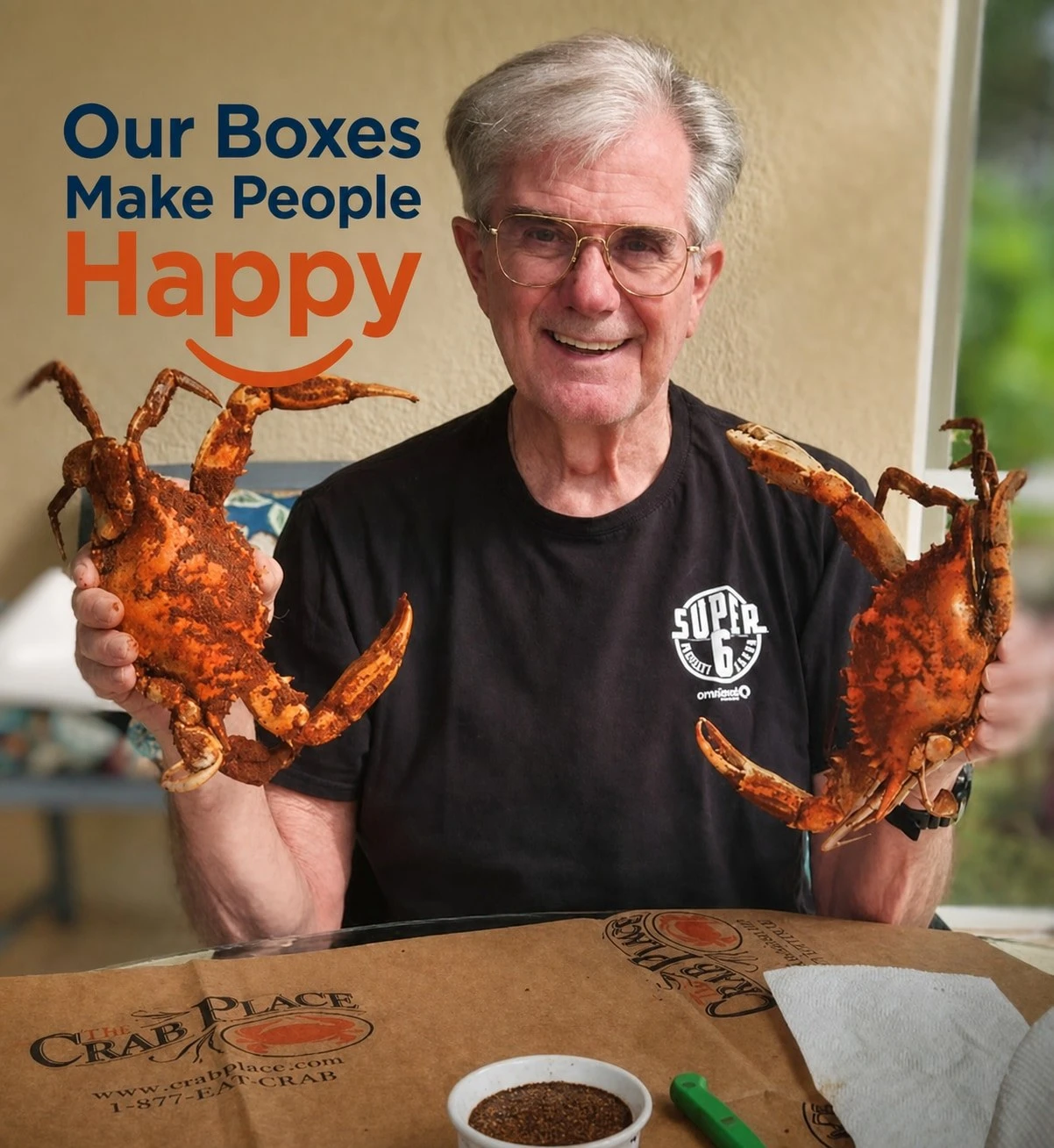 A smiling man holding two steamed Maryland blue crabs over a Crab Place box, with the words Our Boxes Make People Happy