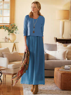 Image of a woman walking through her living room wearing the blue Cassie Dress