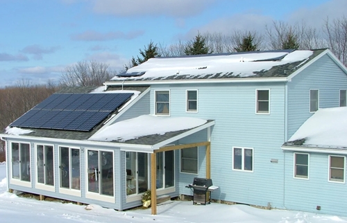 Photovoltaic panels on the roof with snow, with a snow shovel in