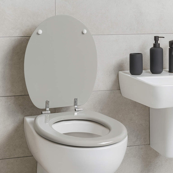 Grey toilet seat fitted on white ceramic toilet next to white sink with black accessories