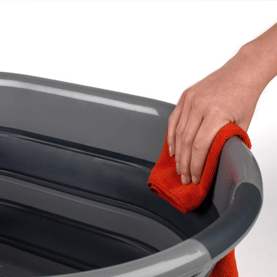 Hand wiping grey plastic tub with orange cloth, showing cleaning in progress