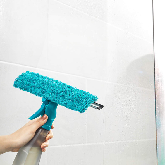 Window cleaning spray with blue microfibre pad shown in use on glass surface