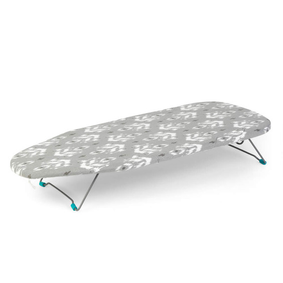 Grey patterned tabletop ironing board with metal foldable legs, shown at an angle