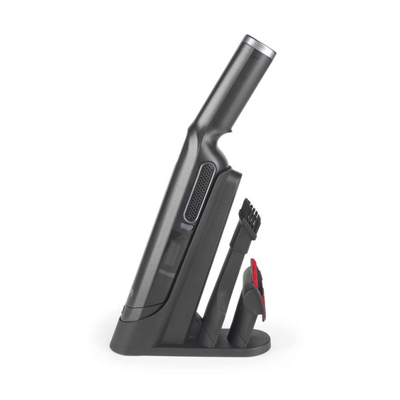 Cordless handheld vacuum cleaner in silver, side view on charging base with attachments