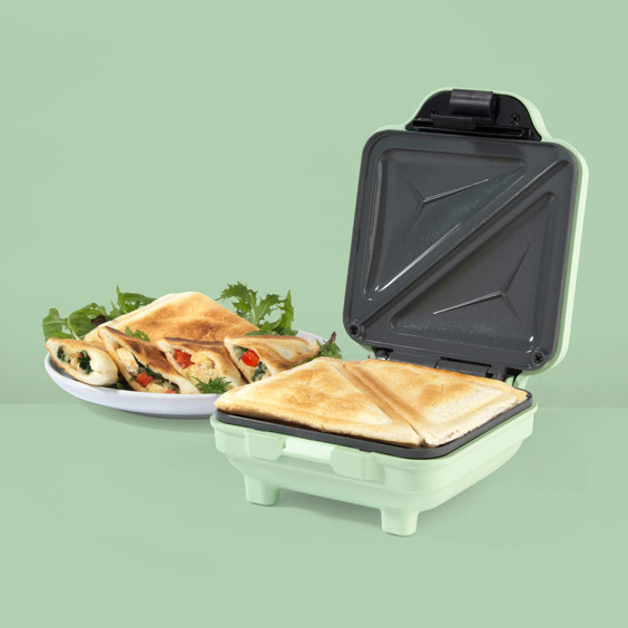 Green sandwich maker with toasted sandwiches and salad on a plate