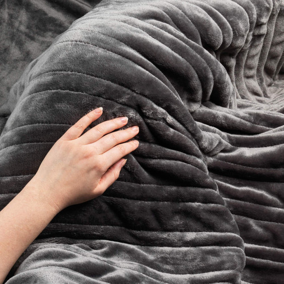 Hand touching soft grey ribbed throw blanket