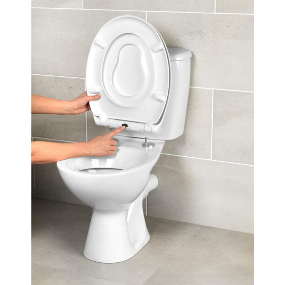 Close-up of hands demonstrating quick release button on white toilet seat.