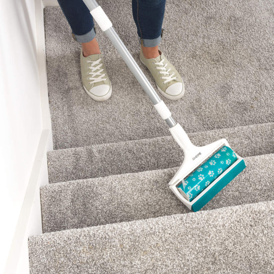 Carpet cleaning roller with handle used on grey carpeted stairs
