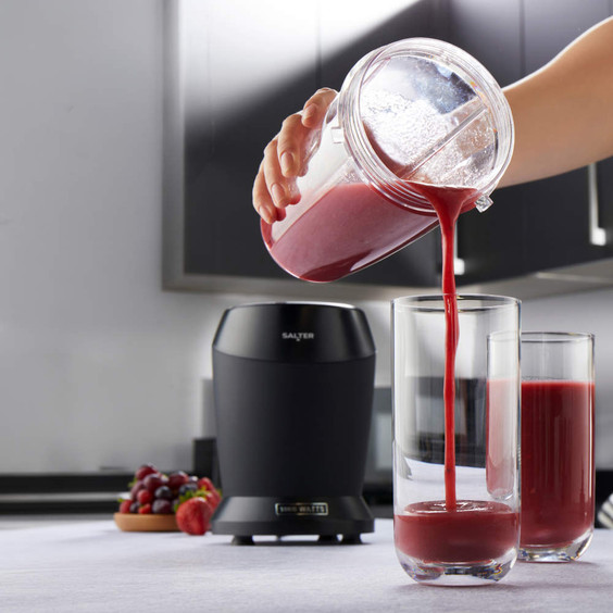 Black Salter blender in kitchen, pouring red fruit smoothie into tall glass