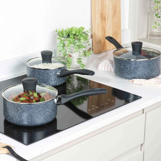 Set of three dark grey non-stick saucepans with glass lids on a kitchen hob