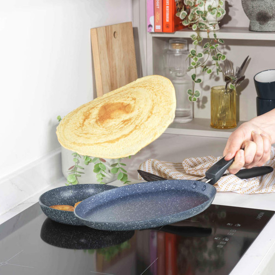 Non-stick blue pancake pan flipping a cooked pancake on induction hob