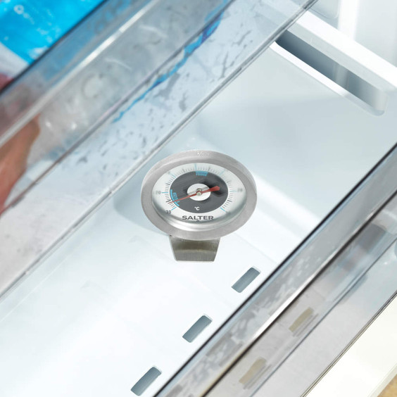 Fridge thermometer standing on shelf for monitoring temperature, interior view