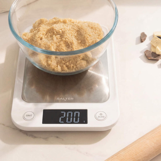 Digital kitchen scale displaying 200 grams with glass bowl of brown sugar