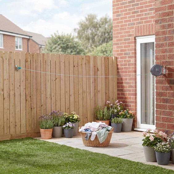Retractable outdoor washing line installed between house wall and wooden fence