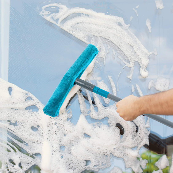 Blue microfibre window cleaning tool wiping soap suds from glass