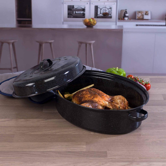 Black oval roasting tin with lid, shown with cooked chicken inside on kitchen worktop