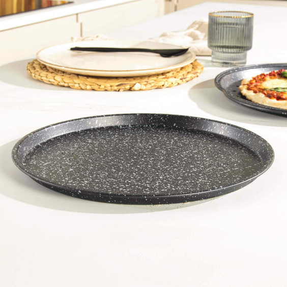 Black speckled round pizza tray shown empty on kitchen counter