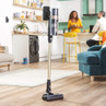 Cordless stick vacuum cleaner standing upright in modern living room with kitchen background