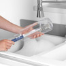 Bottle cleaning brush with blue handle shown in use at kitchen sink