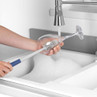 Wine glass cleaning brush in use at kitchen sink, showing ergonomic handle and bristles.