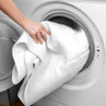 White laundry load being placed into front-loading washing machine