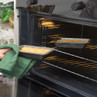 Non-stick loaf tin with crumble topping being placed in an oven, kitchen setting.
