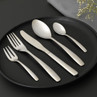 Five-piece silver cutlery set on black plate, includes knife, two forks and two spoons.