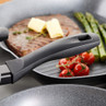 Close-up of grill pan with steak, asparagus and tomatoes, showing non-stick handle