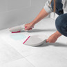 White and pink dustpan and brush set cleaning a spill on a tiled floor