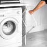 White front-loading washing machine next to pull-out laundry drying rack in modern utility room