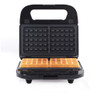 Black waffle maker with two square golden waffles on the hot plate